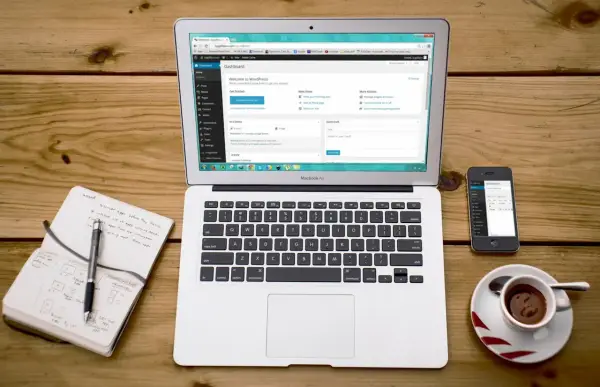 Na laptopie widać panel WordPress, obok smartfon i notatnik. To idealne miejsce do nauki, jak zainstalować WordPress na XAMPP.